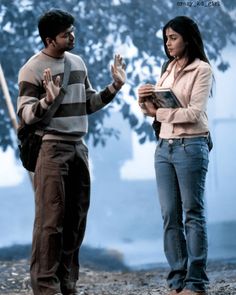 two people standing next to each other with their hands in the air and one person holding a book