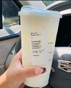 a person holding up a plastic cup in their hand while sitting in the driver's seat