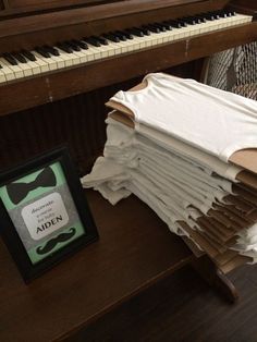 a pile of folded papers sitting on top of a wooden table next to a piano