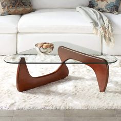 a glass coffee table sitting on top of a white rug in front of a couch