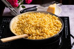 a pan filled with macaroni and cheese on top of a stove next to a spatula