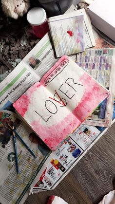 an open book with the word love written on it sitting on top of newspaper pages