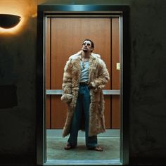 a man standing in front of a door wearing a fur coat