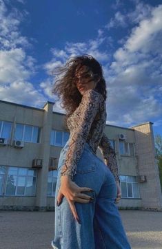 a woman standing in front of a building with her back to the camera and arms around her body