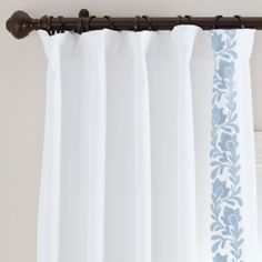 white curtains with blue floral designs hanging on a curtain rod