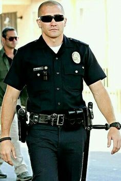 a police officer walking down the street with his hand in his pocket and sunglasses on