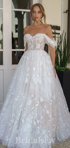 a woman in a white wedding dress standing outside