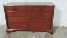 a wooden dresser with many drawers on it's sides and gold hardware at the top