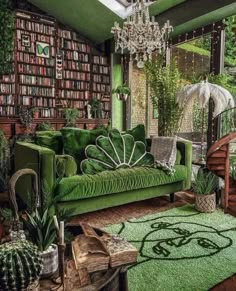 a green couch sitting in front of a book shelf filled with lots of books and plants