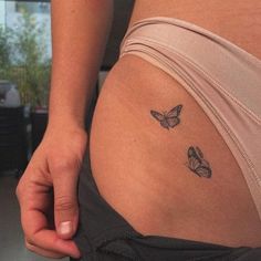 a close up of a person's stomach with two butterflies on the side of her belly