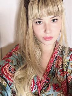 a woman with long blonde hair wearing a flowered shirt and bow in her hair