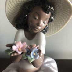 a ceramic figurine wearing a hat and holding flowers