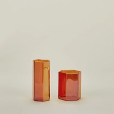 two orange vases sitting next to each other on a white surface with no one around them