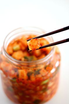 a spoon with some food in it on top of a glass jar and chopsticks