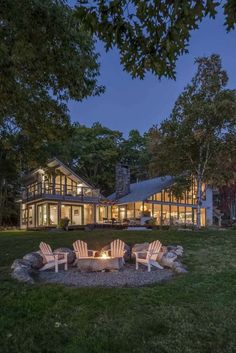 a fire pit sitting in the middle of a lush green field next to a house