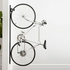 a bike hanging from the side of a white wall next to a potted plant