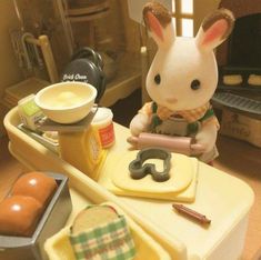 a toy rabbit sitting on top of a counter next to food and utensils