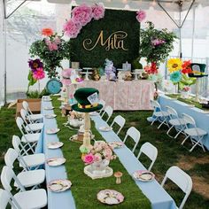 a table set up for a tea party under a tent with flowers and plates on it