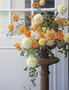 a vase filled with lots of flowers next to a white door window sill on top of a wooden pole