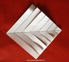 an origami piece on a red surface with white paper folded in the shape of arrows