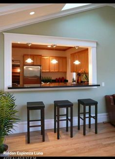 a living room with three stools and a kitchen in the backround behind it