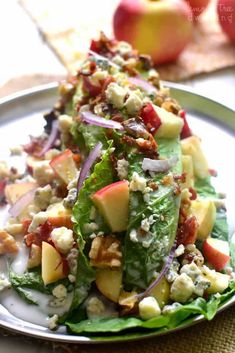 a salad with lettuce, apples and other toppings on a white plate