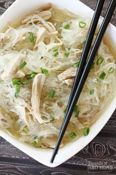 two black chopsticks sticking out of a bowl of chicken noodle soup