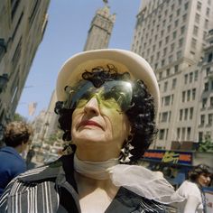 a woman wearing sun glasses and a white hat in the middle of a busy city