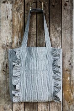 a gray and white striped tote bag hanging on a wooden wall with wood planks in the background