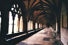 an arched hallway with stone flooring and benches lined up against the wall in front of it