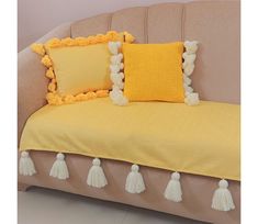 a couch with yellow pillows and tassels on it