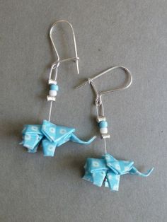 the earrings are made out of blue paper with white dots on them and an elephant dangling from it's earwires