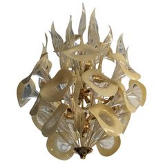 a chandelier made out of glass and gold colored metal pieces with leaves on each side