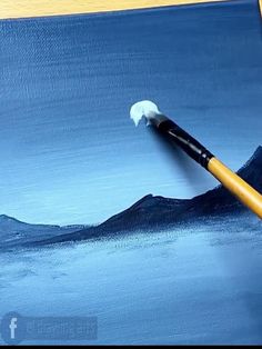 a paintbrush is being used to paint a landscape