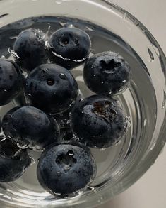 blueberries are in a glass bowl with water