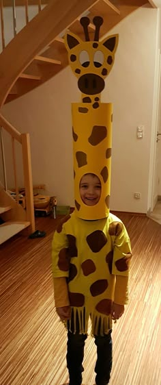 a young child wearing a giraffe costume standing in front of a stair case