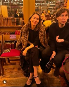 two people sitting next to each other in a room full of books and stuffed animals