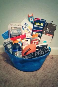 a blue bucket filled with sports items on top of a carpeted floor next to a wall