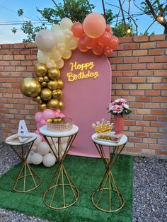 a birthday party with balloons and decorations on the grass in front of a brick wall