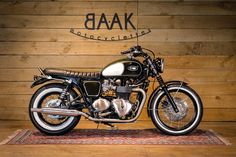 a black and white motorcycle parked on top of a wooden floor next to a wall