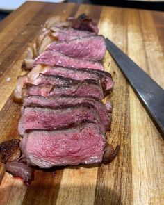 a piece of steak on a cutting board next to a knife