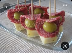 small appetizers with olives and meat are on a glass platter, ready to be eaten