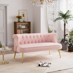 a pink couch sitting in a living room next to a chandelier and table