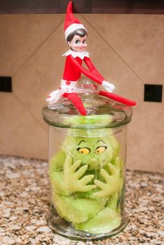 an elf sitting on top of a jar filled with green stuff