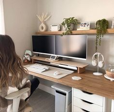 a woman sitting at a computer desk with two monitors and keyboard on top of it