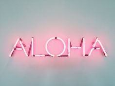 the word aloha spelled in neon pink letters on a light blue background,