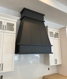 a kitchen with white cabinets and black stove hood