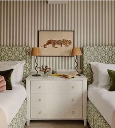 two twin beds in a bedroom with wallpapered walls and green pillows on them