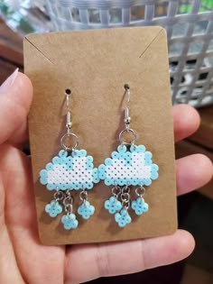 a pair of blue and white beaded earrings on a brown card with a basket in the background