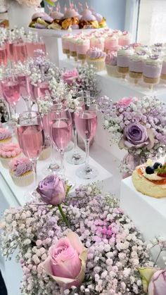 there are many cupcakes on the table with flowers and wine glasses next to them